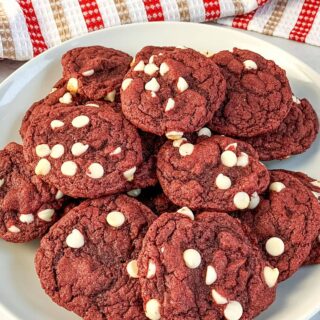 A large plate filled with red velvet cake mix cookies with white chocolate chips.