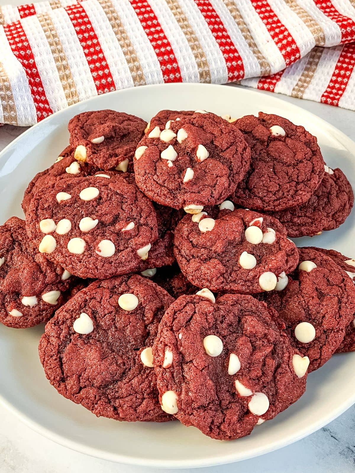 A large plate filled with red velvet cake mix cookies with white chocolate chips.