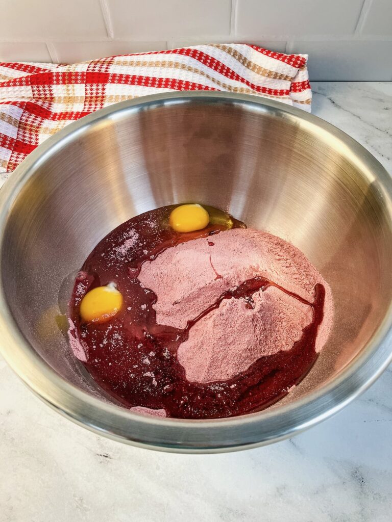 A mixing bowl with a red velvet cake mix powder, 2 eggs, and vegetable oil.