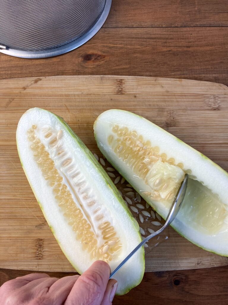 Scooping seeds out of the cucumbers with a spoon.