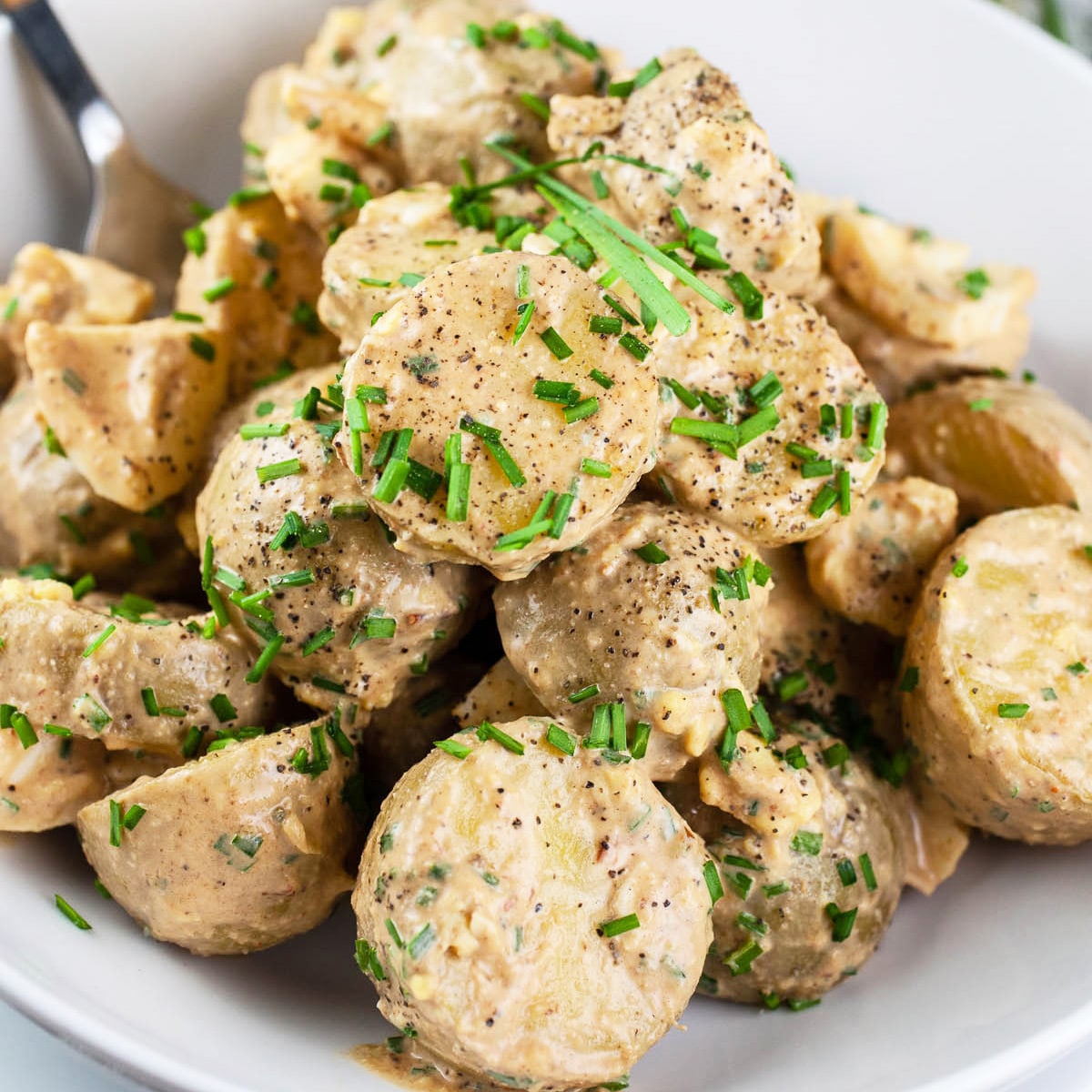 Chipotle potato salad in a white bowl and topped with chives.