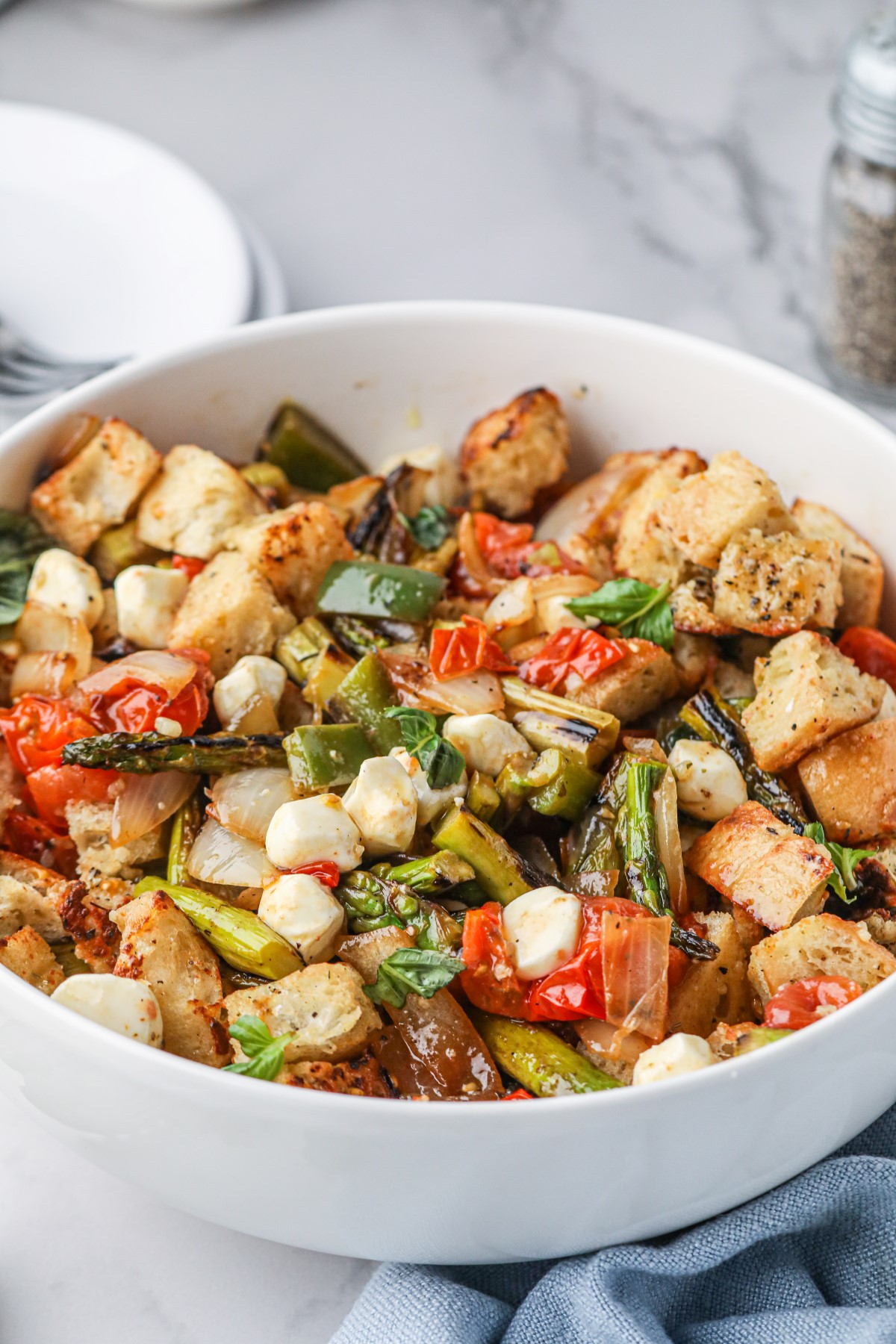 A white serving bowl filled with grilled asparagus panzanella.