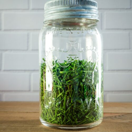 A mason jar filled with dehydrated chives.