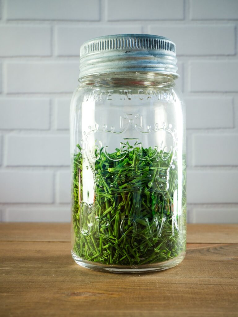 A mason jar filled with dehydrated chives.