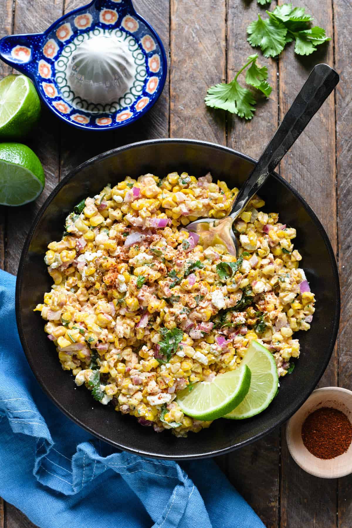 A black serving bowl filled with Mexican roasted street corn salad.