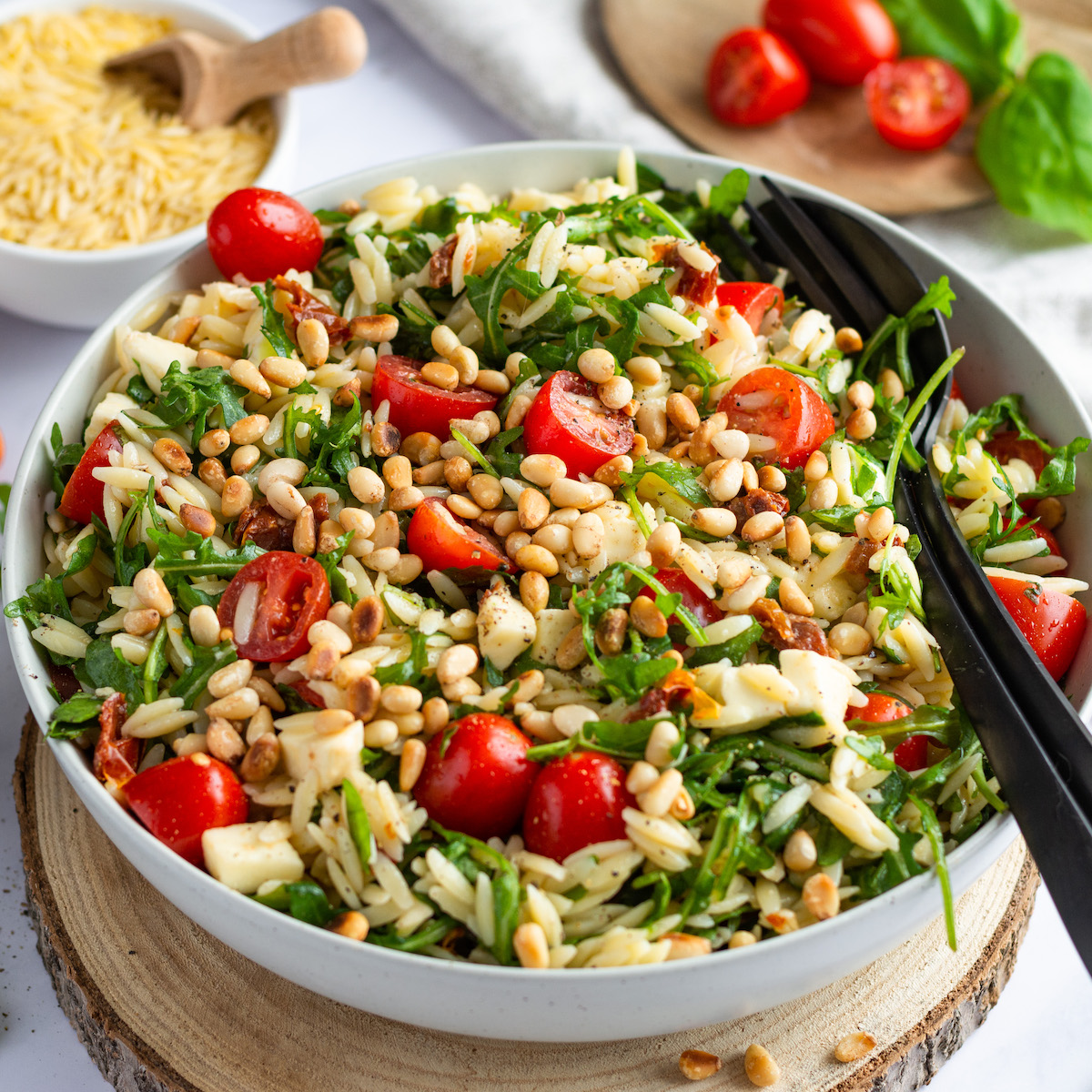 White serving bowl filled with risoni Mediterranean salad.