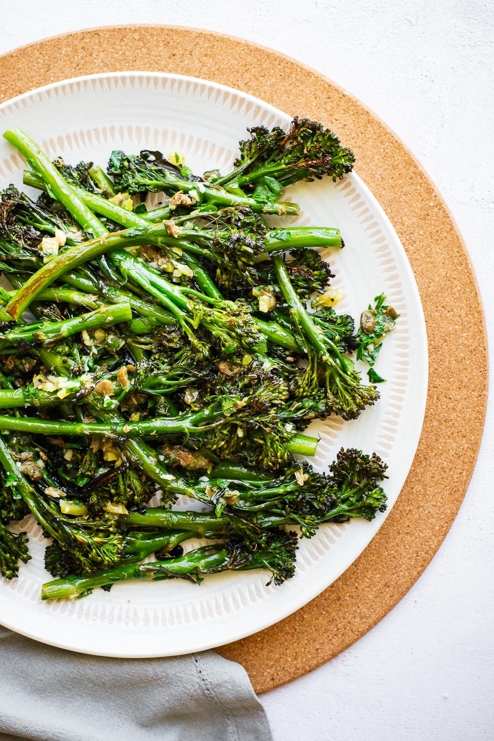 A white plate filled with charred broccolini.
