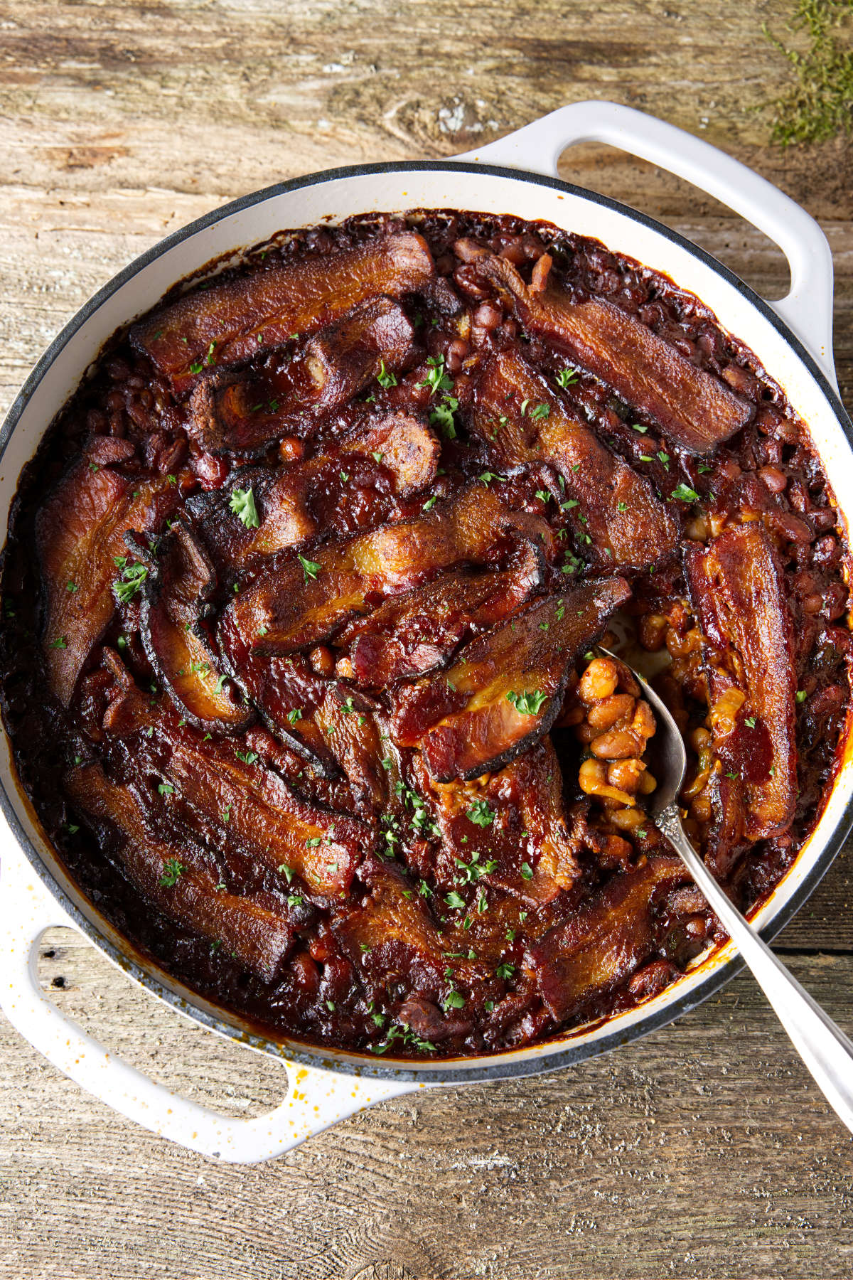 Dutch oven filled with smoked, baked beans and topped with bacon.