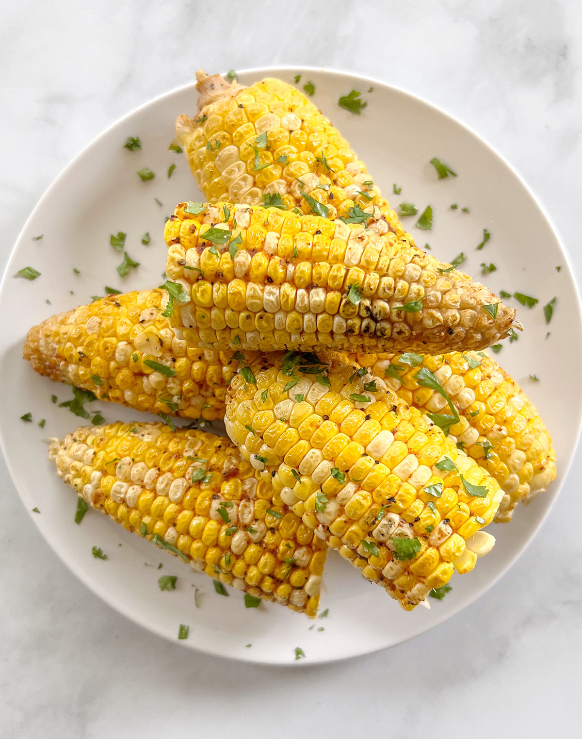 Smoked corn on the cub on a white plate.