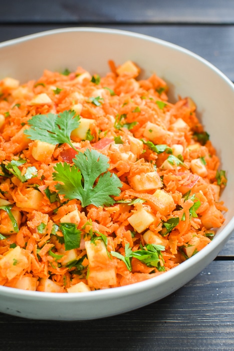 Carrot and apple salad in a white bowl.