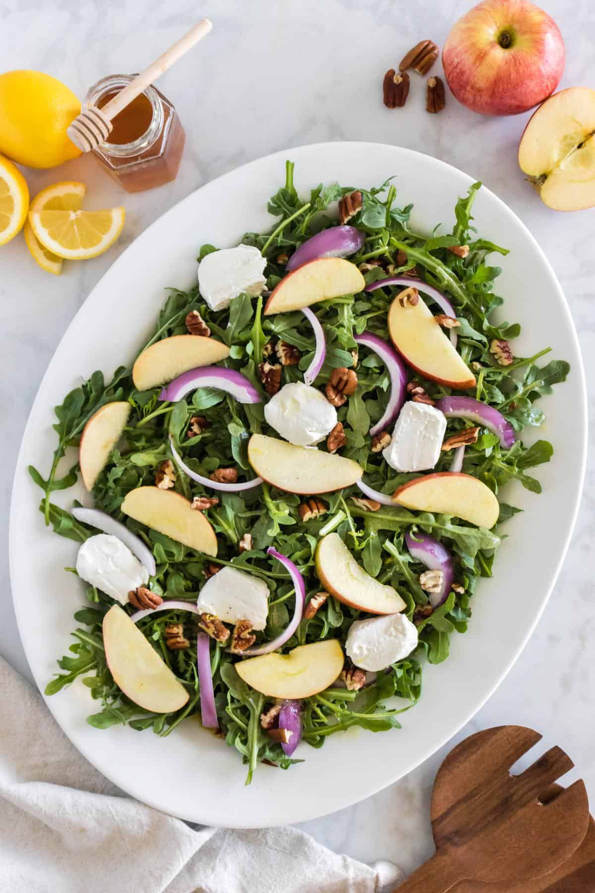 Apple arugula salad on a white serving platter.