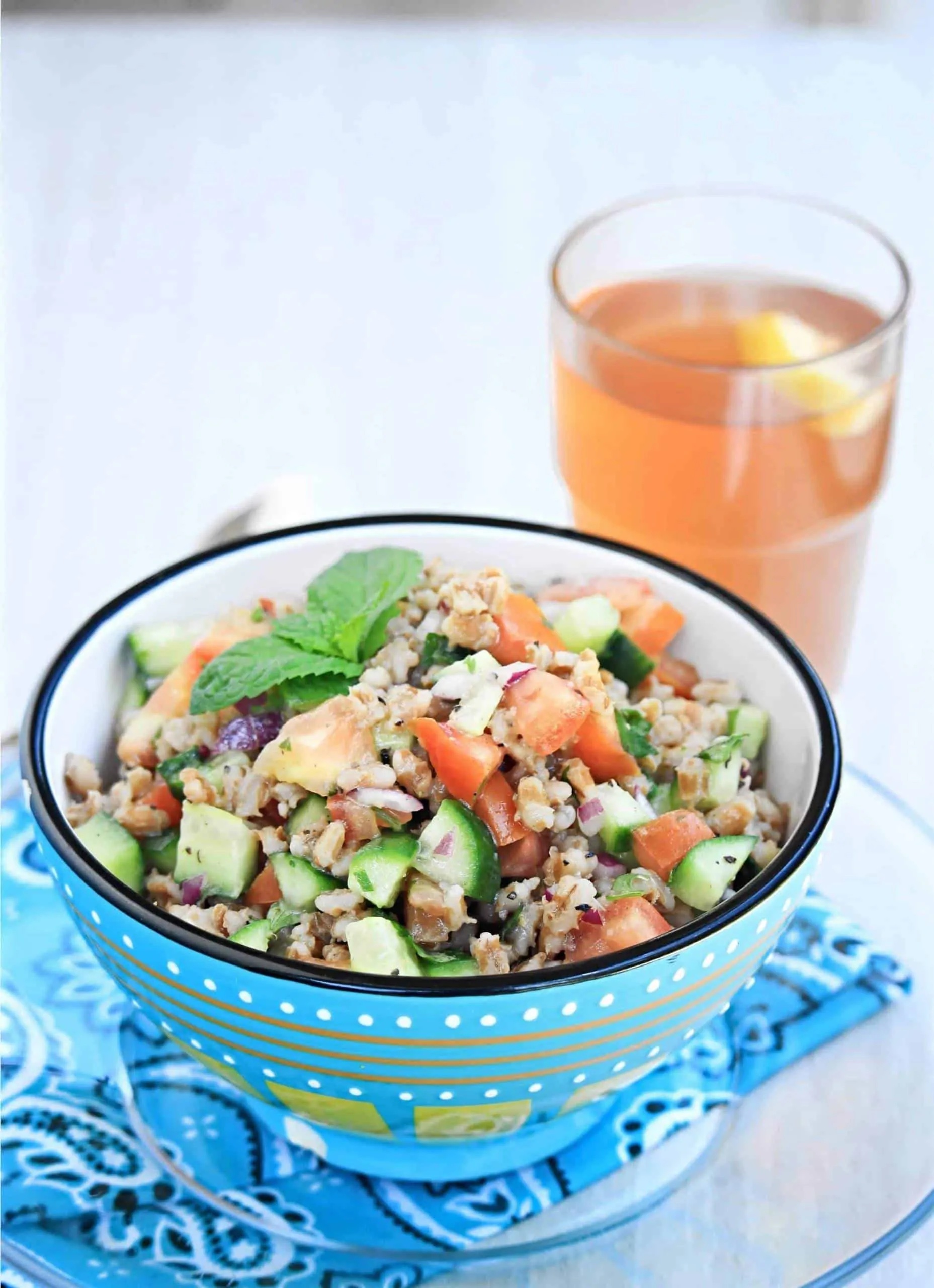 A blue bowl filled with fresh barley and cucumber salad.