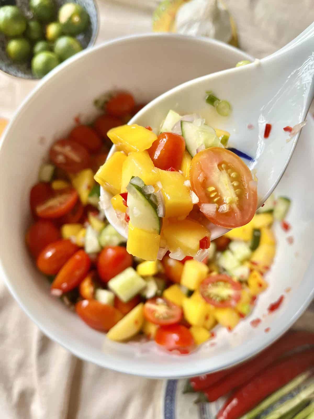 Cucumber and mango salad in a white bowl.