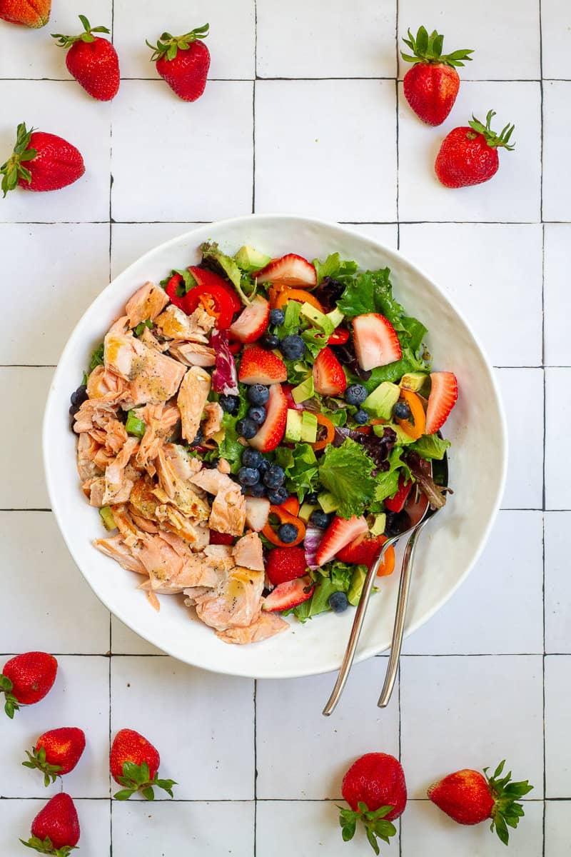 Salmon strawberry salad on a white plate.