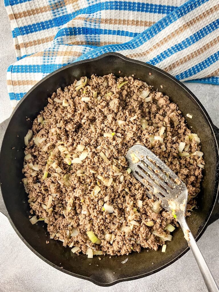 Cooked ground beef and onions in a cast iron skillet.