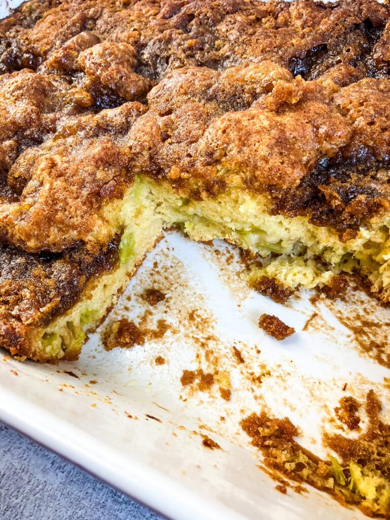 Rhubarb coffee cake in a baking dish with a slice removed to show the inside of the cake.
