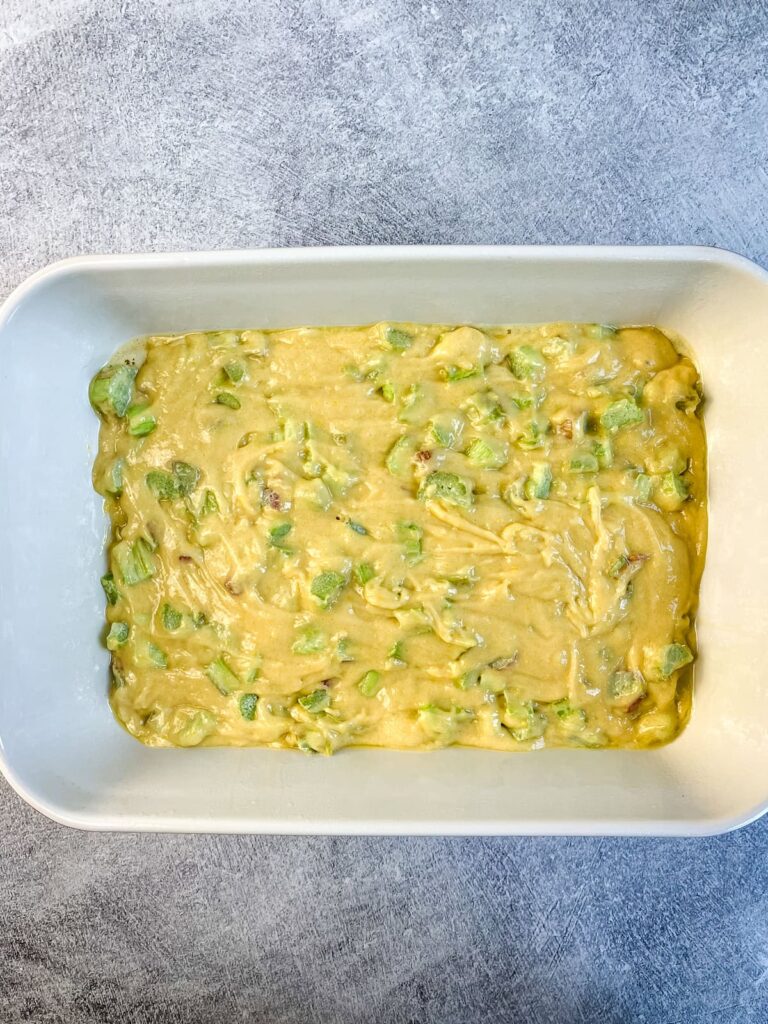 Rhubarb coffee cake batter spread in a 9x13 baking dish.