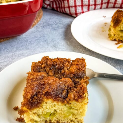 A slice of homemade rhubarb coffee cake on a white plate.