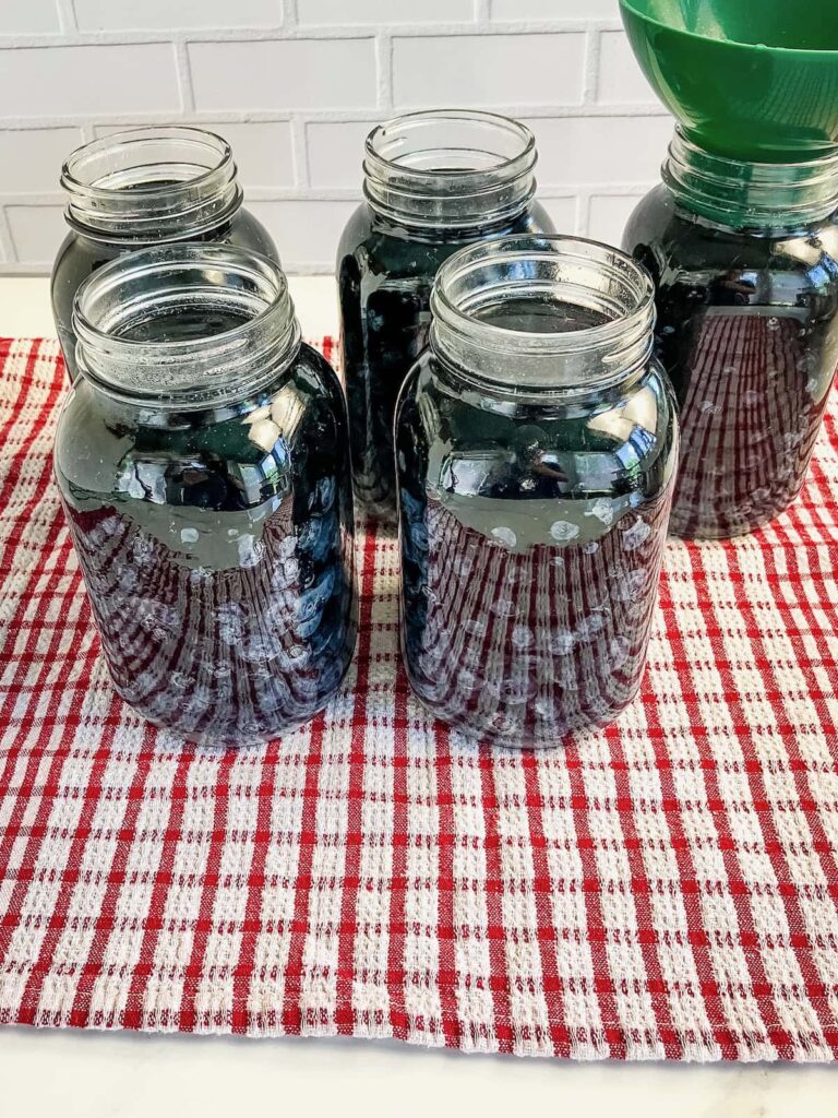 Filling mason jars of blueberries with hot water.