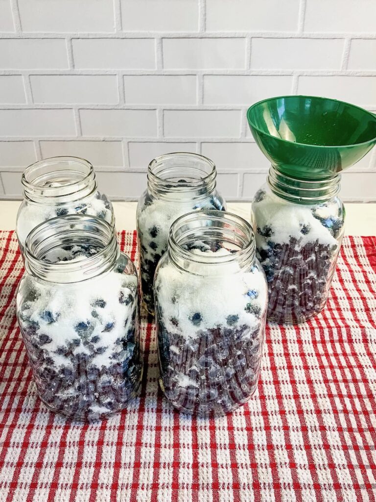 Using a green canning funnel to help add sugar to can blueberries.