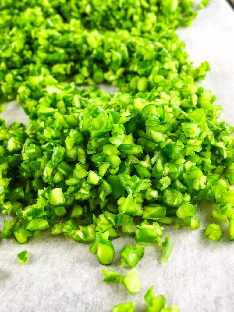 Finely chopped garlic scapes on a parchment lined dehydrator tray.