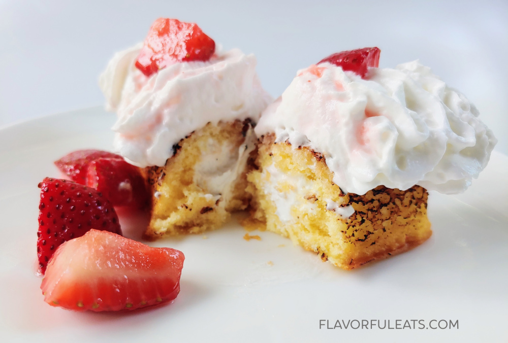 Twinkie strawberry shortcake cut in half on a white plate.
