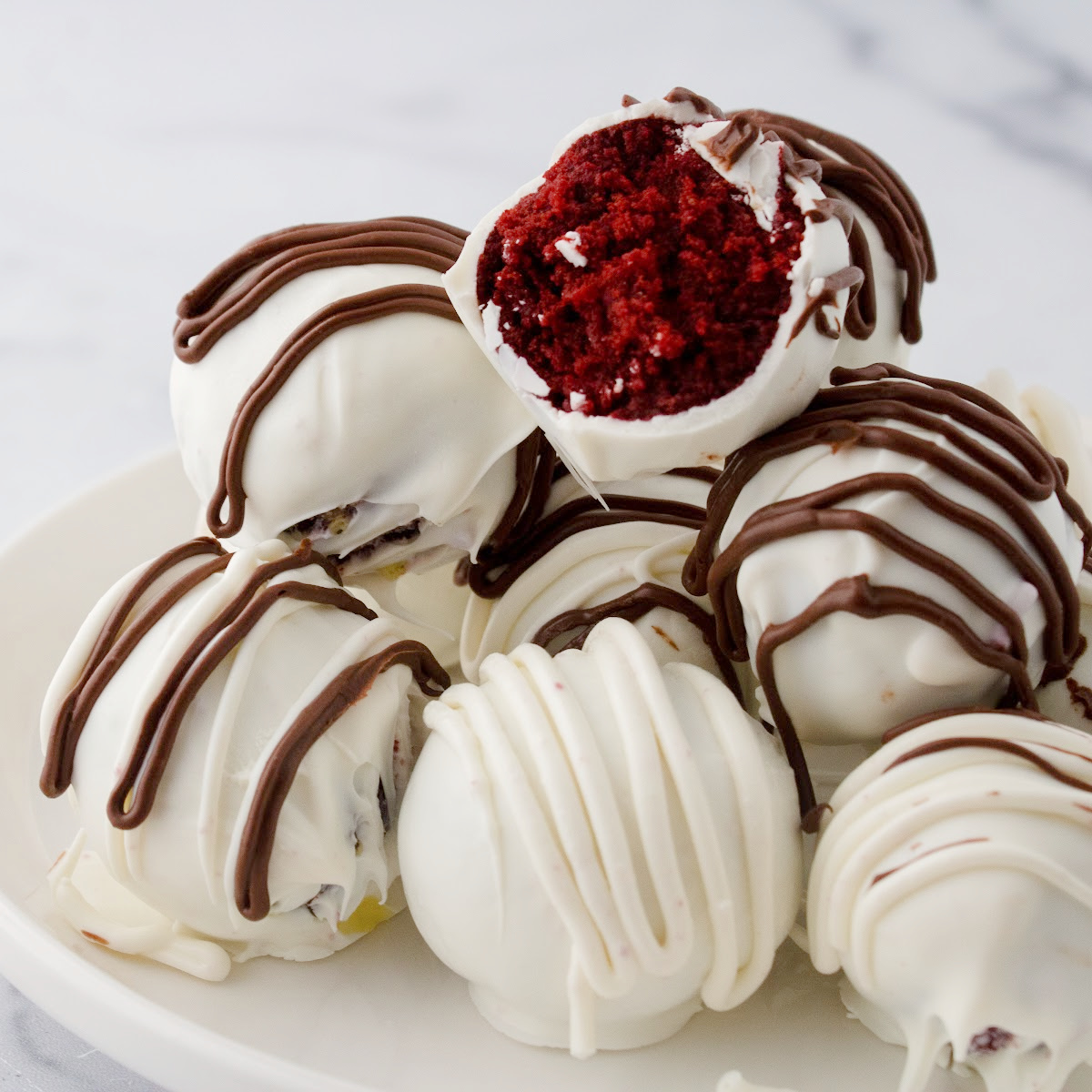Red velvet cake balls coated in white chocolate on a plate.