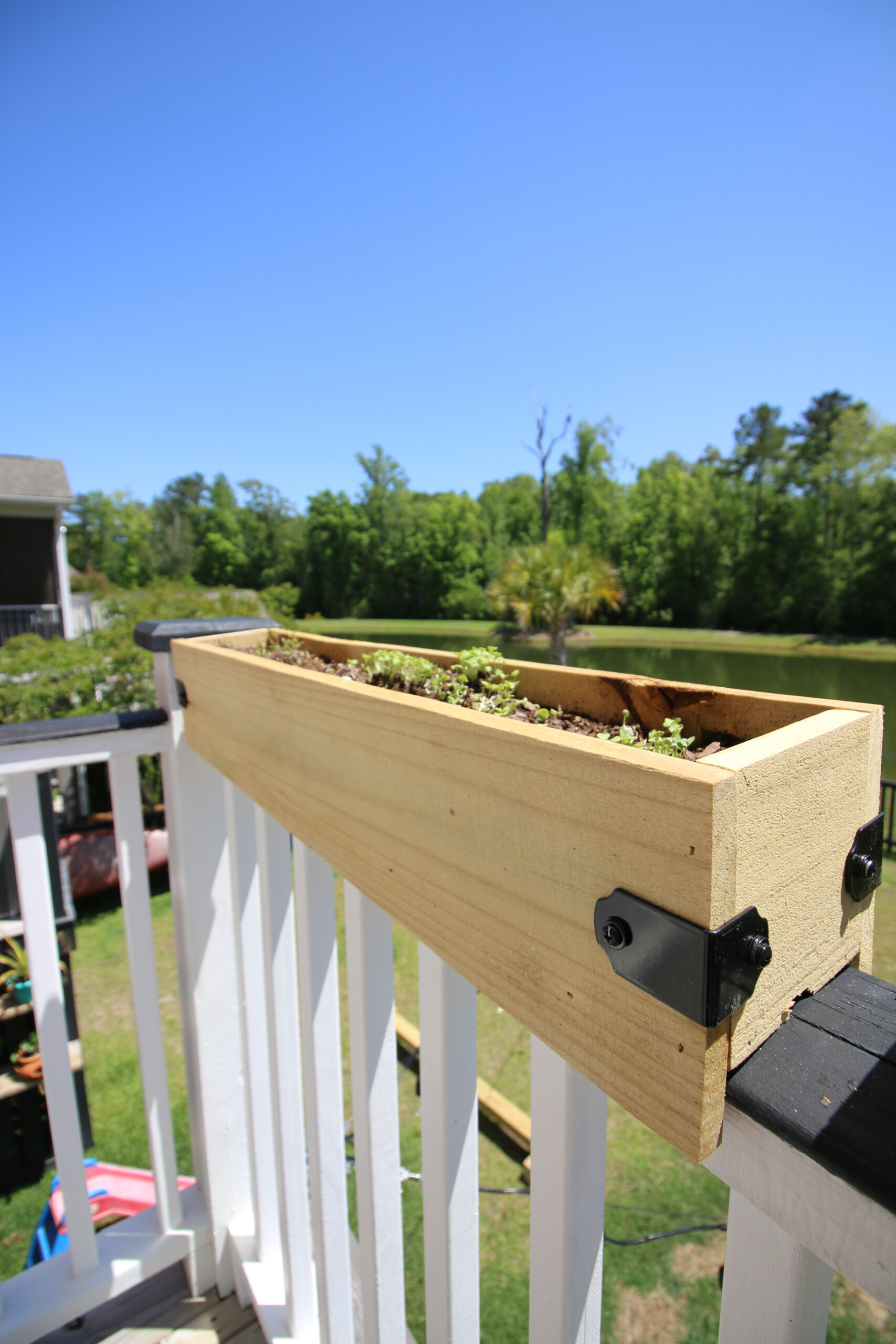 DIY wooden planter box on a deck railing.