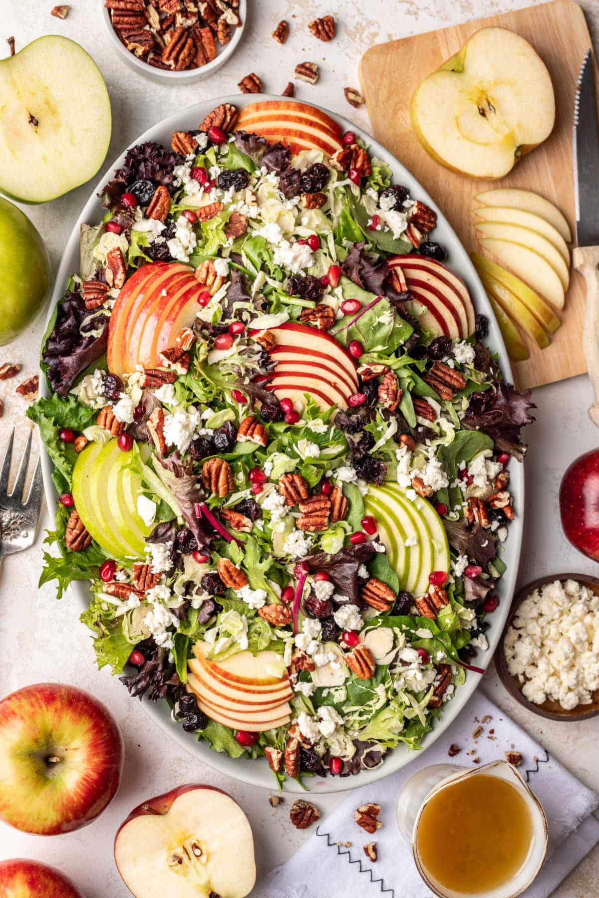 Fall salad with apples and walnuts on a white serving tray.