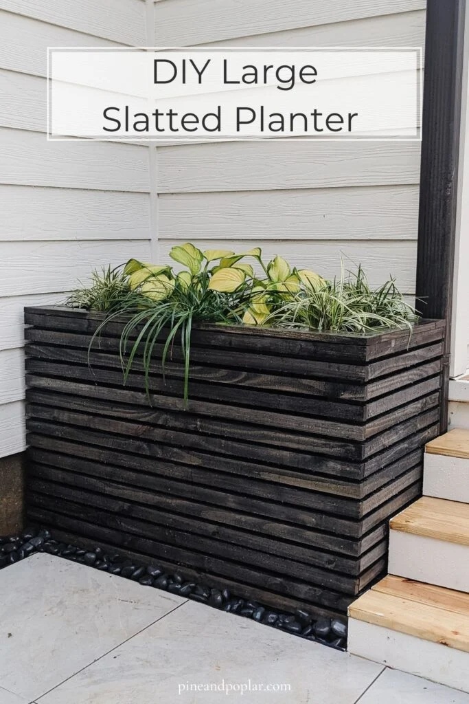 Large wood slatted planter filled with plants next to a door.