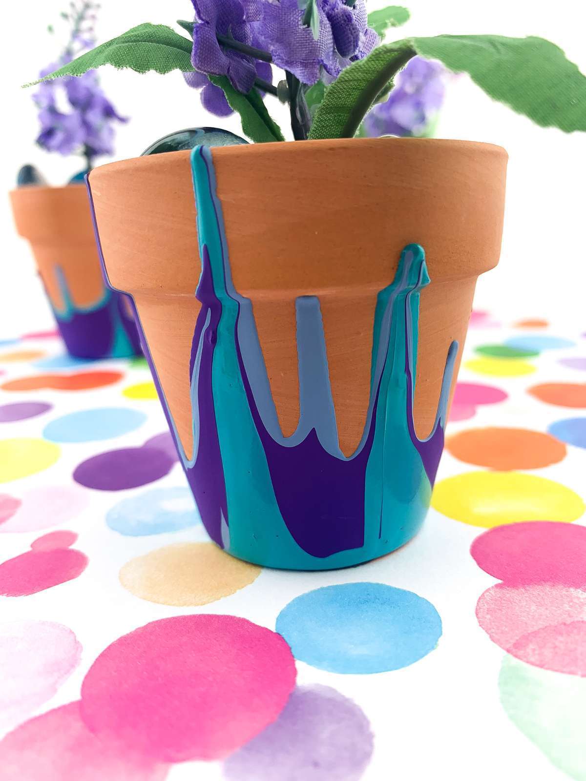 Terra cotta flower pot with blue and purple paint patterns.