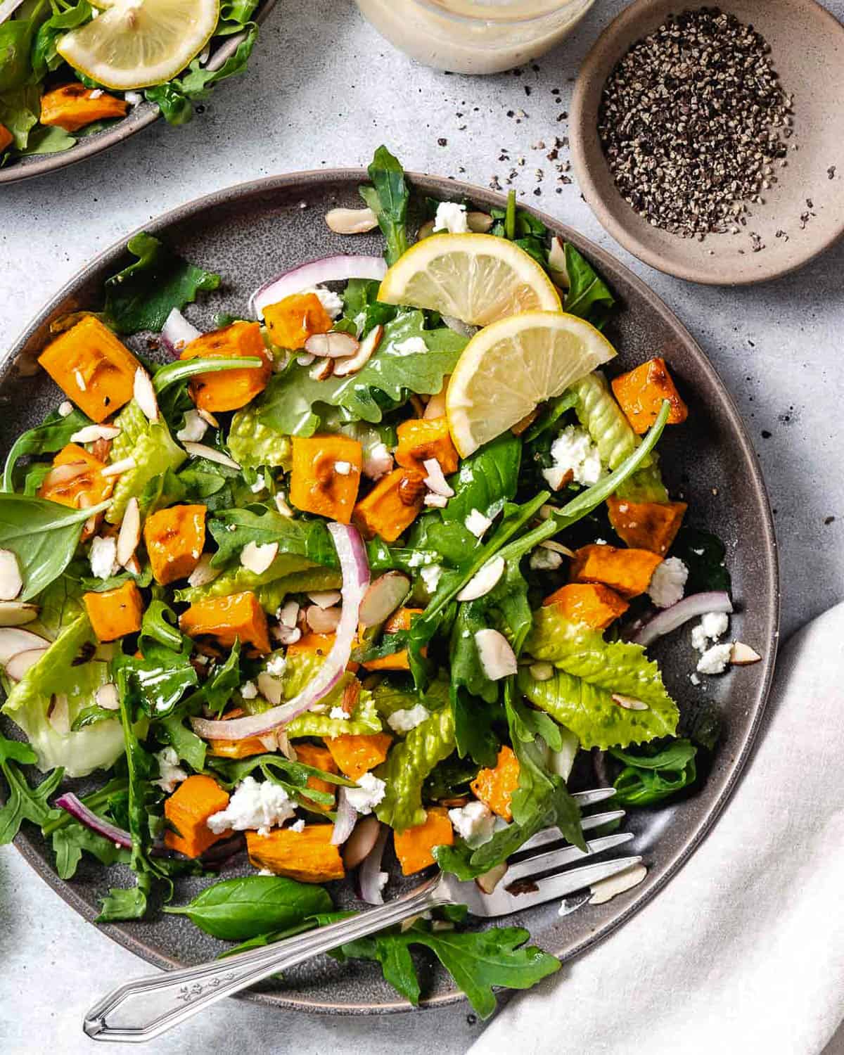 A grey plate filled with homemade arugula and sweet potato salad.