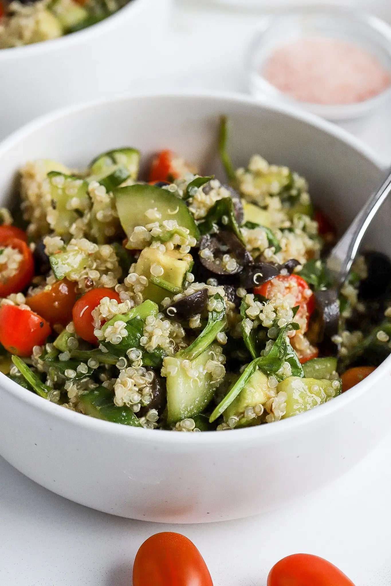 Quinoa spinach and avocado salad in a white bowl.