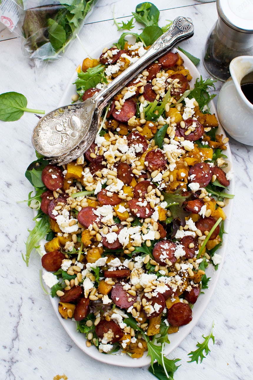 A white serving platter of roasted butternut squash and chorizo salad.