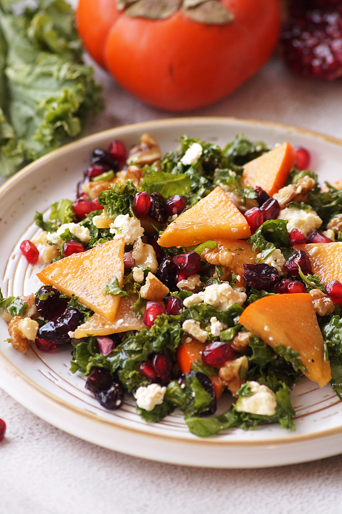Kale and persimmon salad on a white plate.