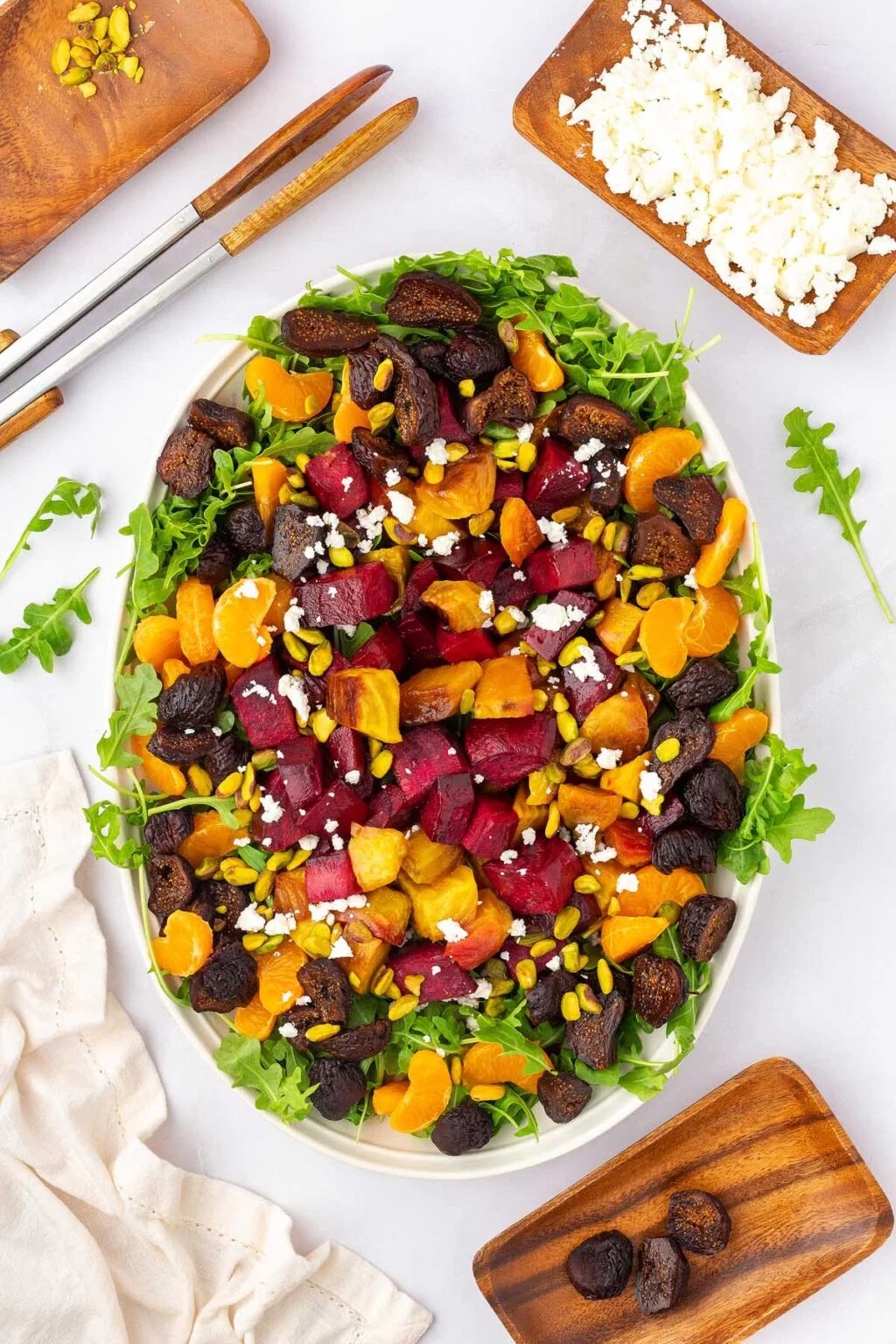 Roasted beet salad with clementines and arugula on a white serving platter.