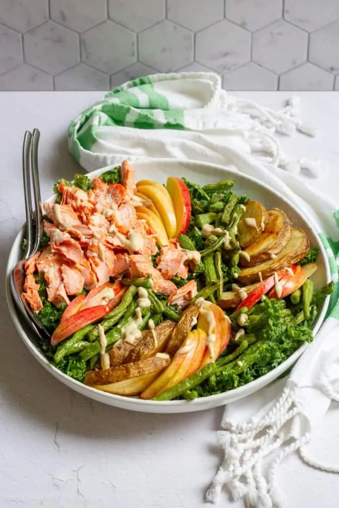 Kale and salmon salad on a white serving tray.