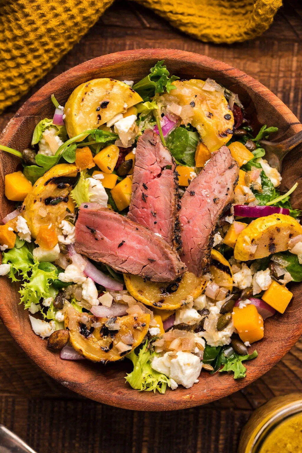 Steak and squash salad in a wooden bowl.
