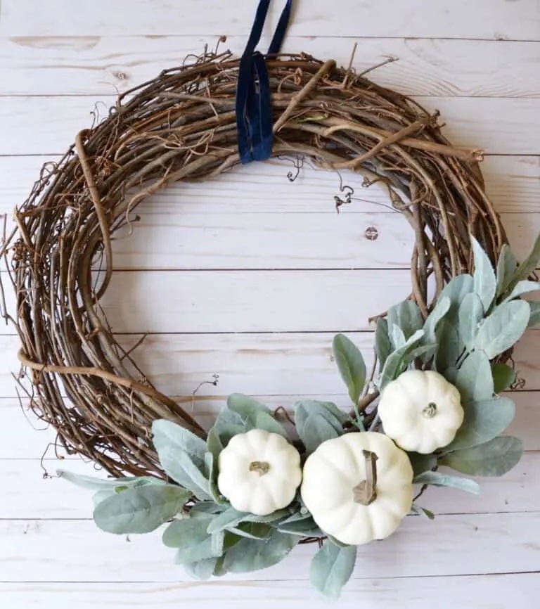 DIY Farmhouse style fall wreath with green leaves and white pumpkins.