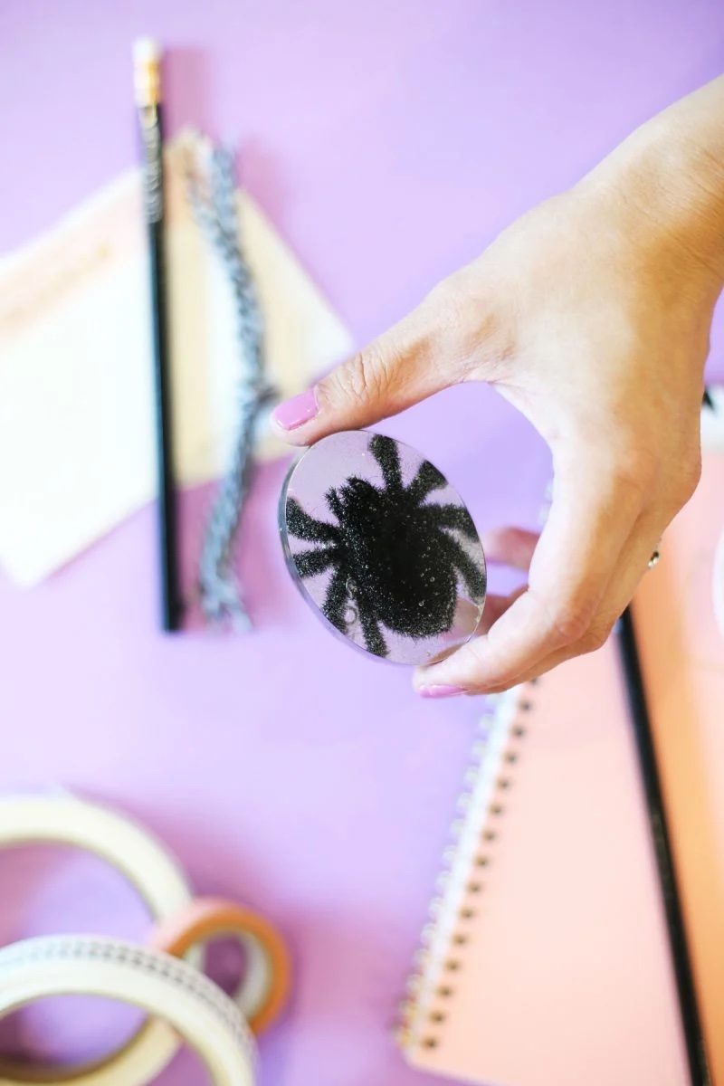 DIY spider paperweight held up over a desk.