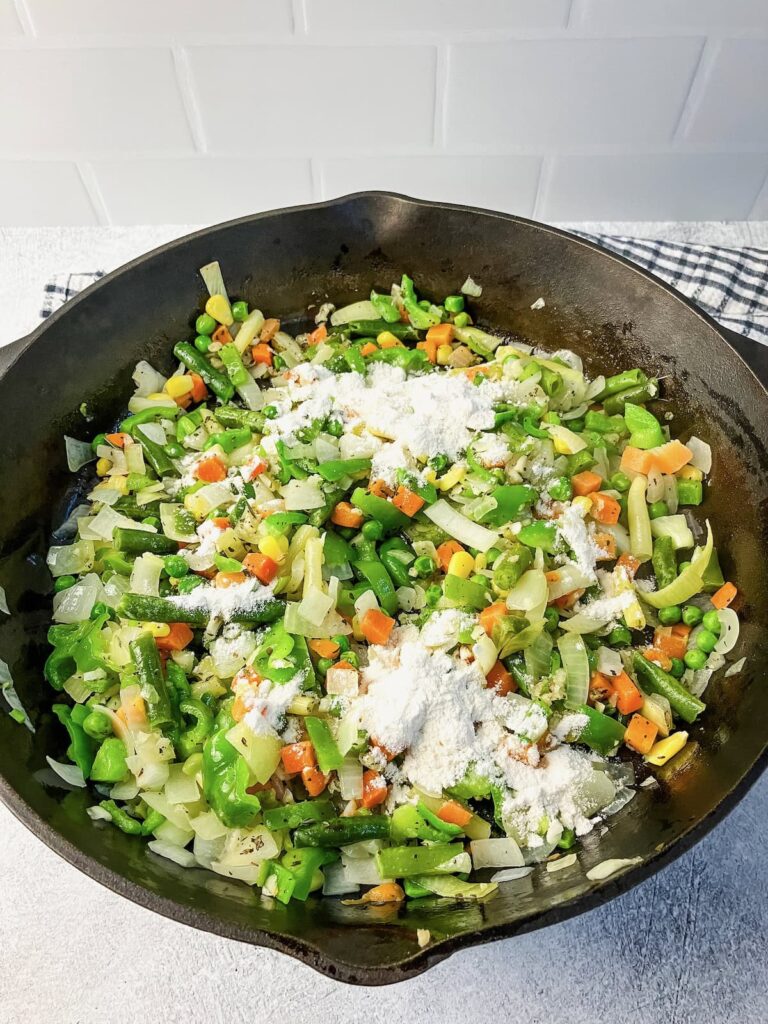 Adding flour to the vegetable mixture.