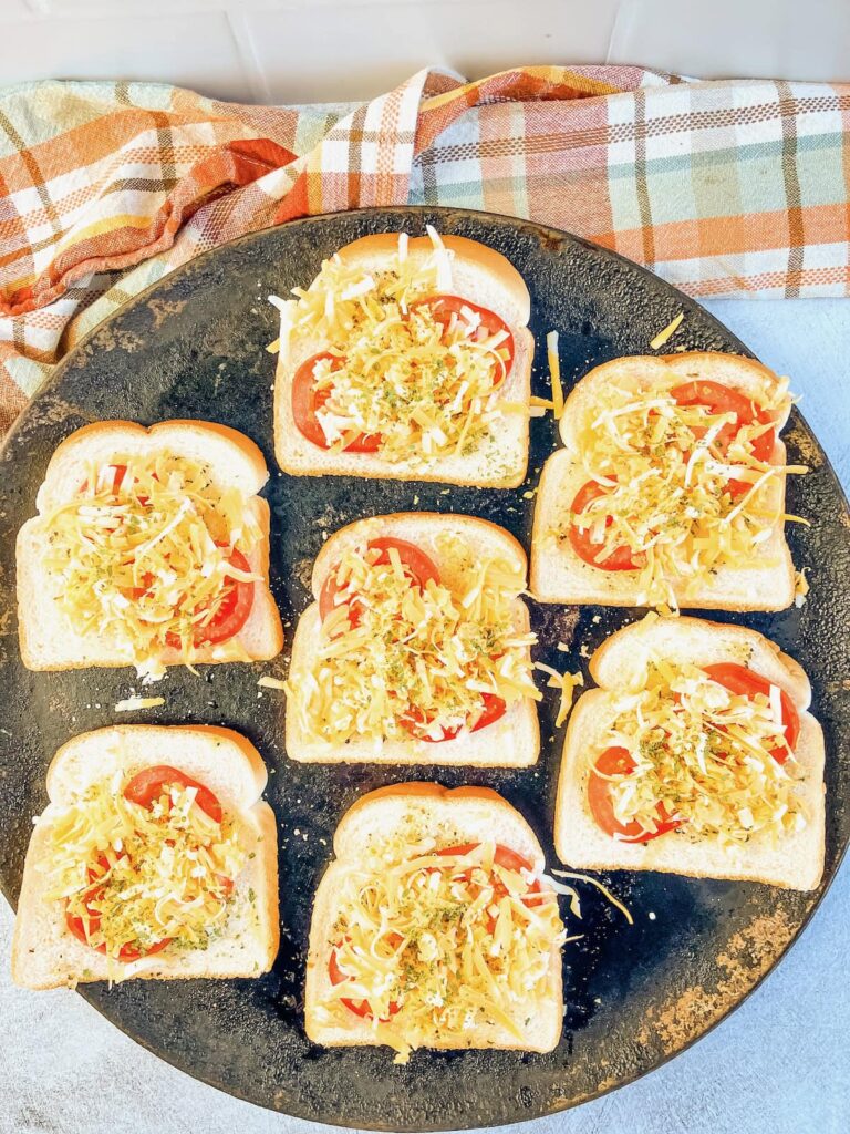 Shredded cheese sprinkled over the tomato slices and bread.