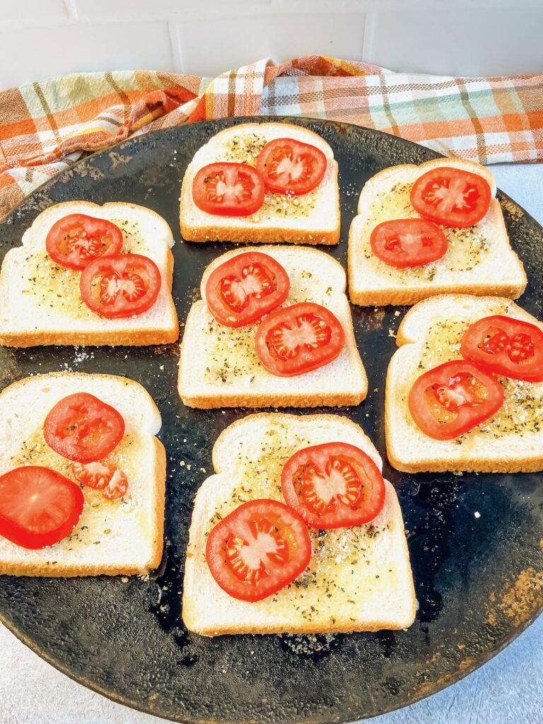 Sliced tomatoes added on top of the garlic bread.