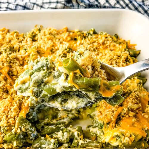 Serving spoon of homemade green bean casserole lifting out of the baking dish.