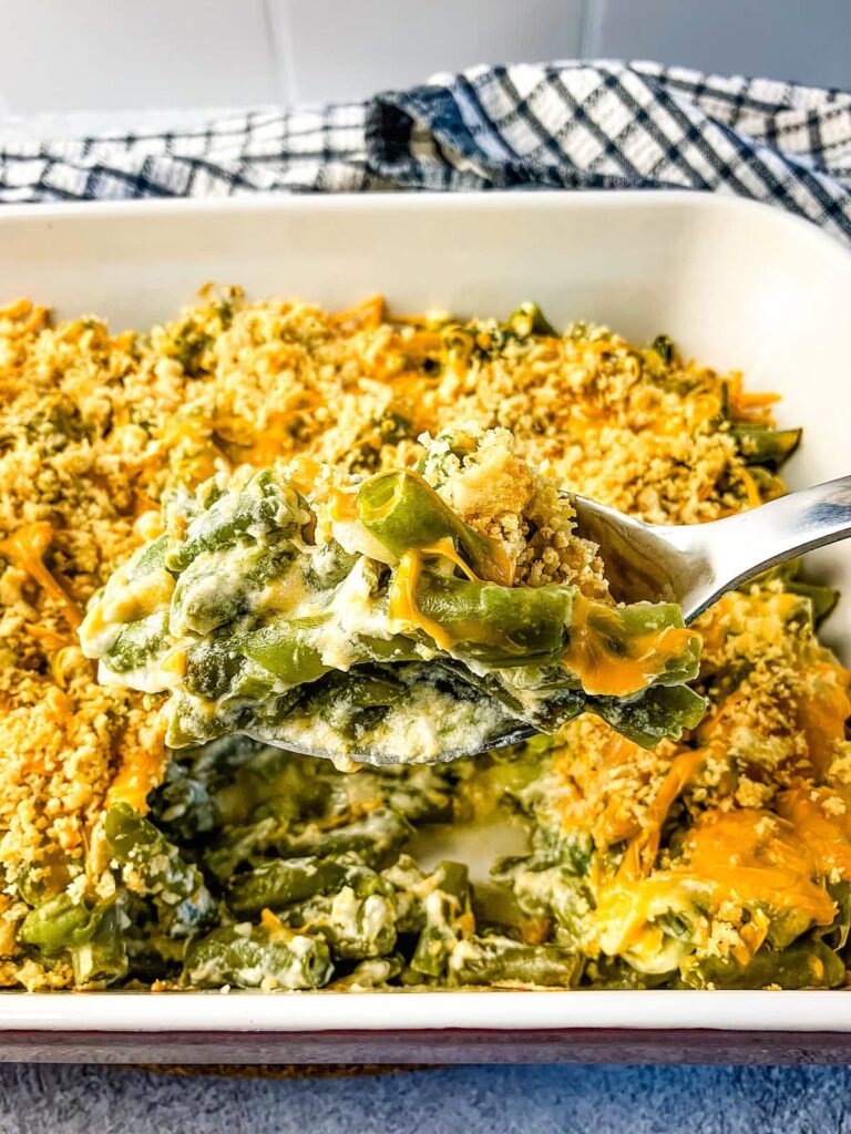 Serving spoon of homemade green bean casserole lifting out of the baking dish.