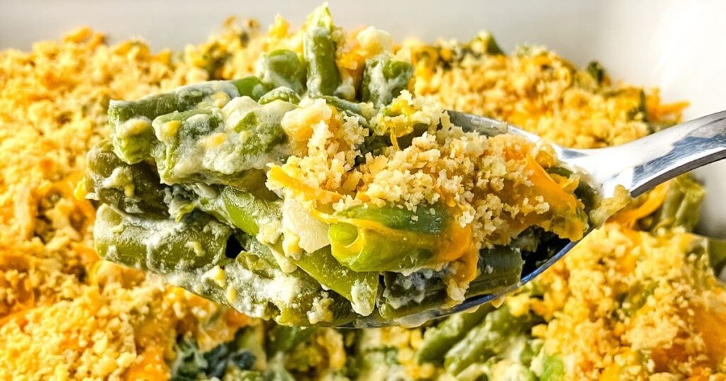 Homemade green bean casserole with a serving spoon full being lifted up.