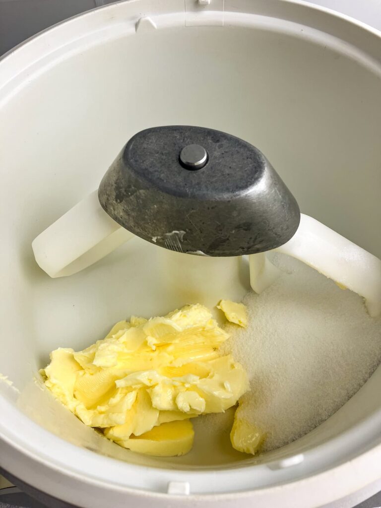 Butter and white sugar in the bowl of a stand mixer.