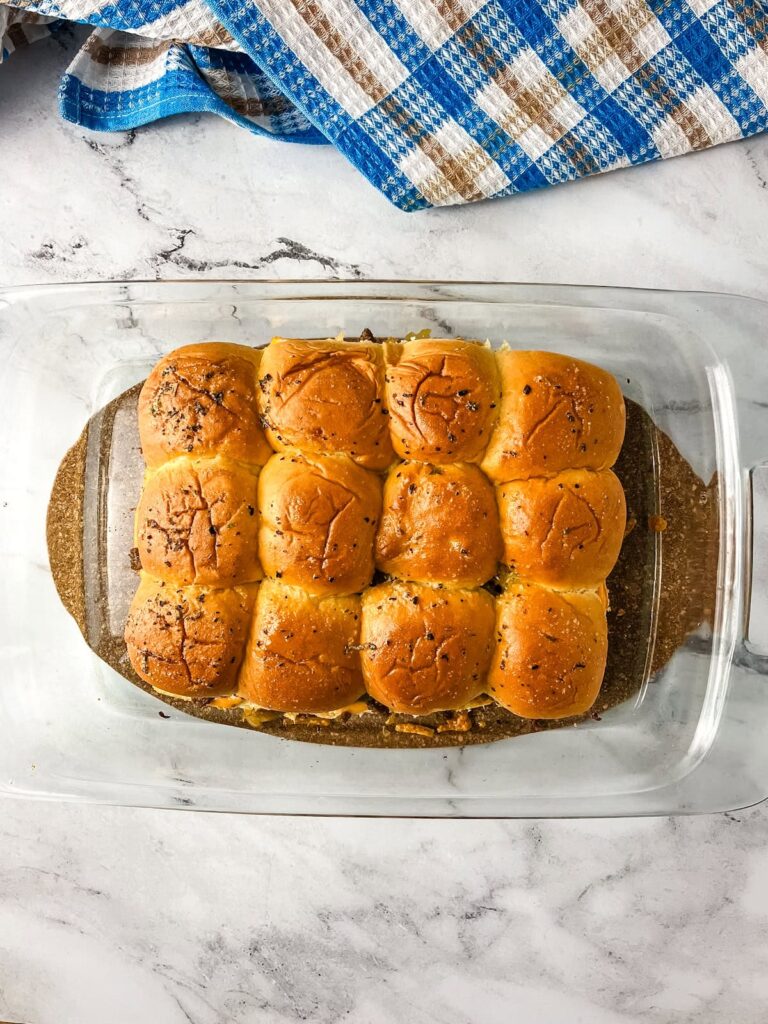 Oven baked cheeseburger sliders cooling on the counter.