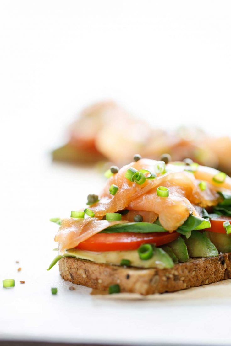 Toast with avocado and smoked salmon on a white plate.