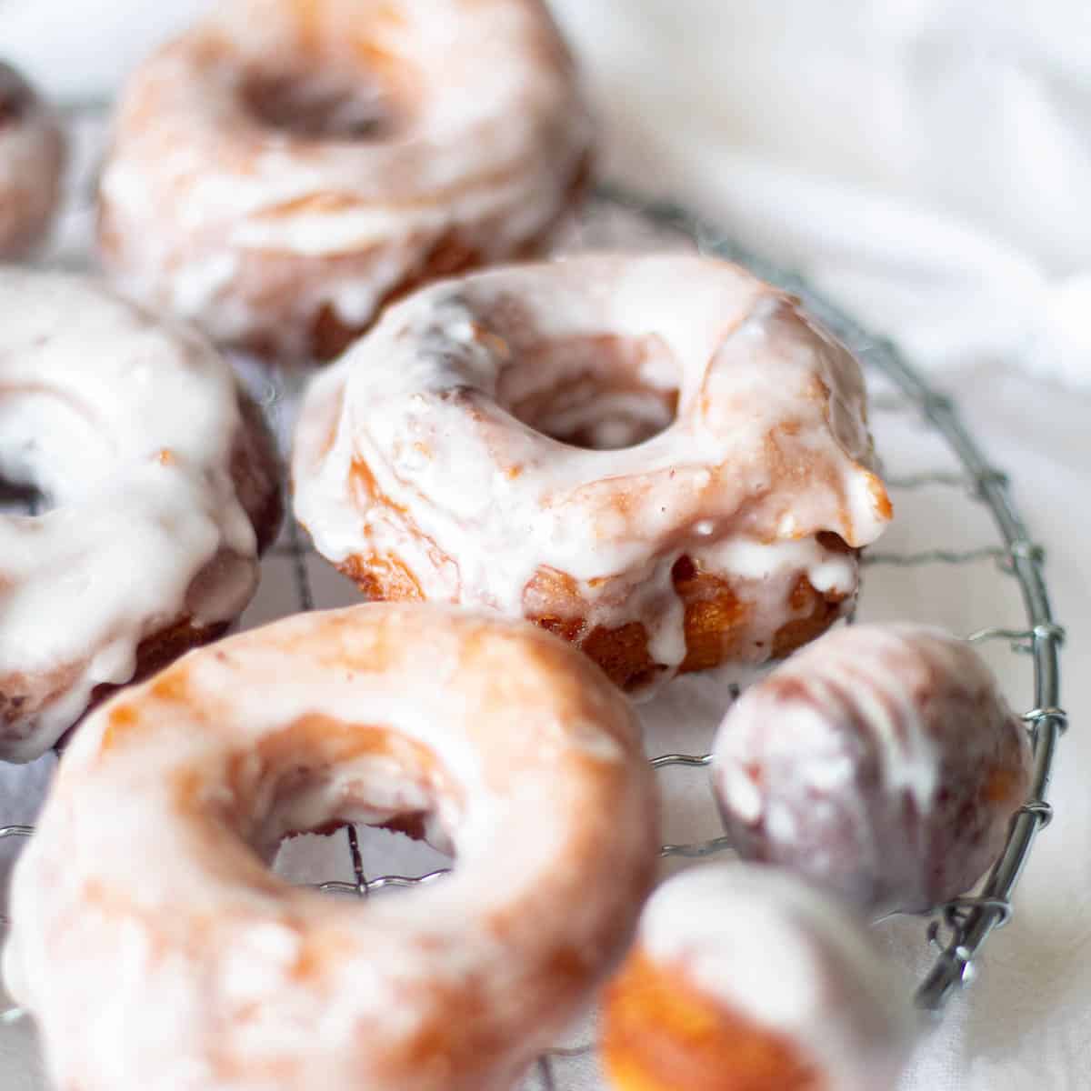 Cinnamon roll donuts on a cooling rack.